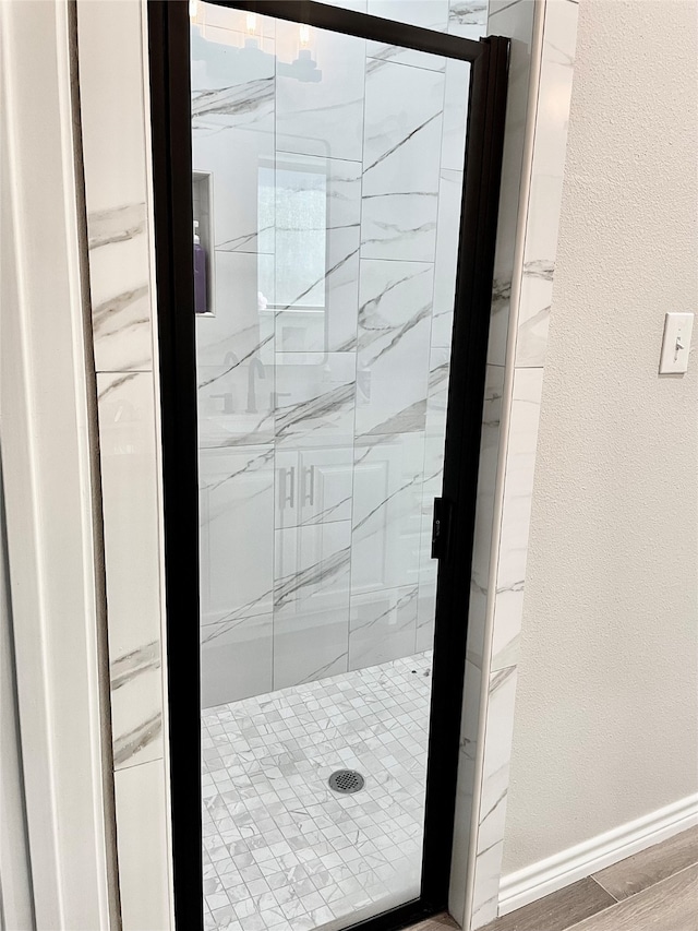 bathroom with hardwood / wood-style floors and a shower with shower door