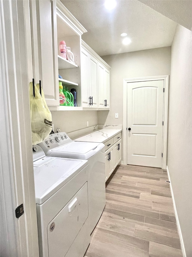 laundry room with cabinets, washer and dryer, and light hardwood / wood-style floors