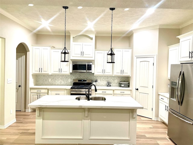 kitchen featuring white cabinetry, appliances with stainless steel finishes, light stone counters, an island with sink, and pendant lighting