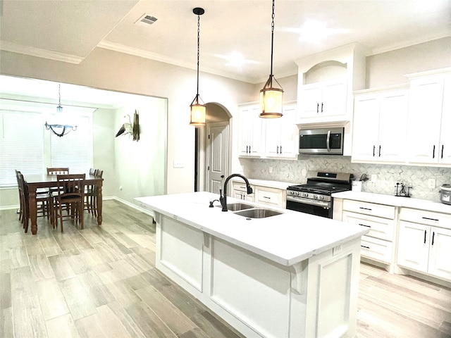 kitchen with stainless steel appliances, a center island with sink, hanging light fixtures, sink, and white cabinetry