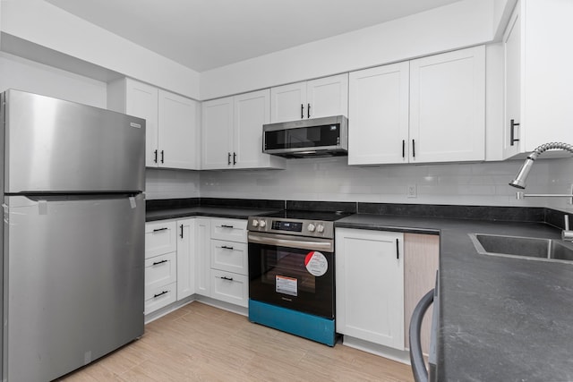 kitchen featuring appliances with stainless steel finishes, tasteful backsplash, white cabinetry, and sink