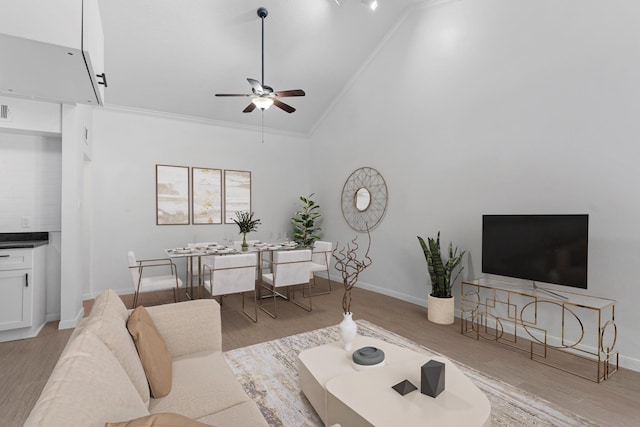 living room featuring ceiling fan, high vaulted ceiling, ornamental molding, and light wood-type flooring