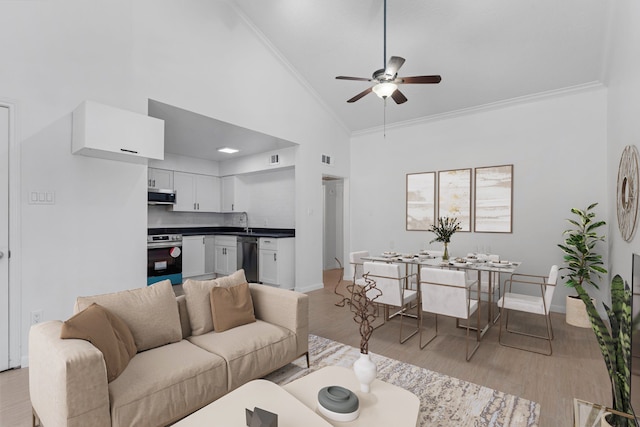 living room featuring high vaulted ceiling, sink, light hardwood / wood-style flooring, ceiling fan, and ornamental molding