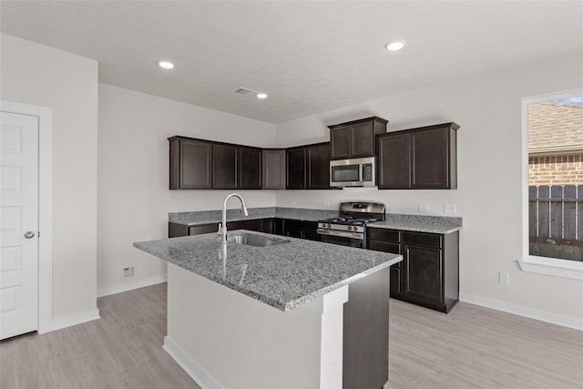 kitchen featuring light stone countertops, appliances with stainless steel finishes, light hardwood / wood-style flooring, and sink