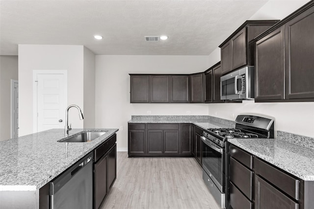 kitchen featuring sink, light hardwood / wood-style flooring, light stone counters, dark brown cabinetry, and stainless steel appliances