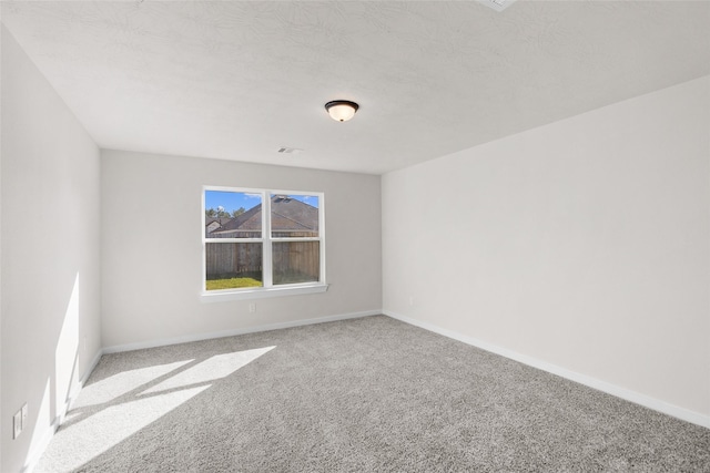 spare room featuring light colored carpet and a textured ceiling