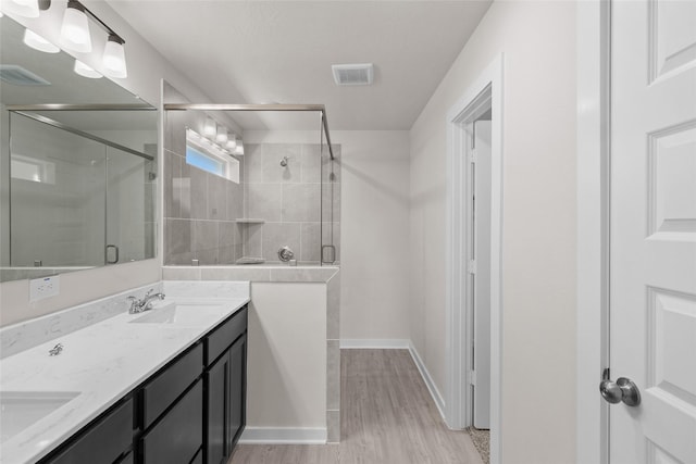 bathroom with hardwood / wood-style flooring, vanity, and walk in shower