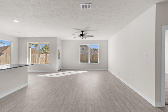 unfurnished living room featuring ceiling fan, light hardwood / wood-style floors, and a textured ceiling