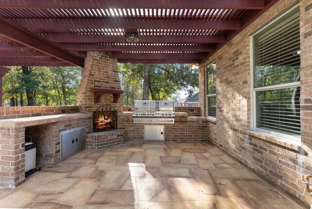 view of patio / terrace featuring an outdoor brick fireplace and an outdoor kitchen