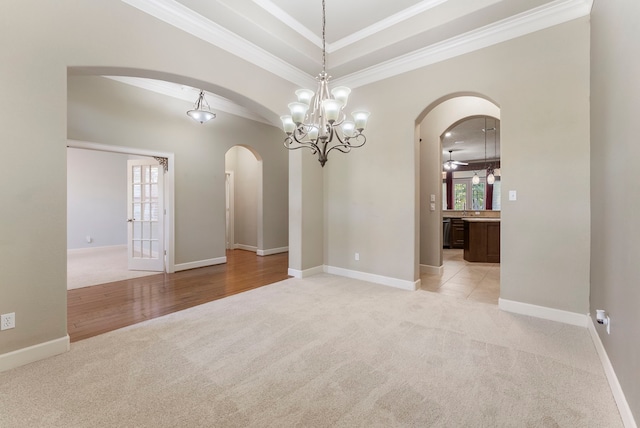 spare room with light carpet, ornamental molding, and a notable chandelier