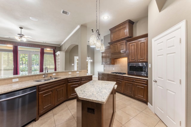 kitchen with crown molding, appliances with stainless steel finishes, decorative light fixtures, sink, and a kitchen island