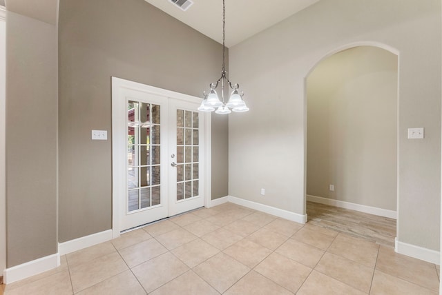 unfurnished dining area featuring a chandelier, light tile patterned floors, and french doors