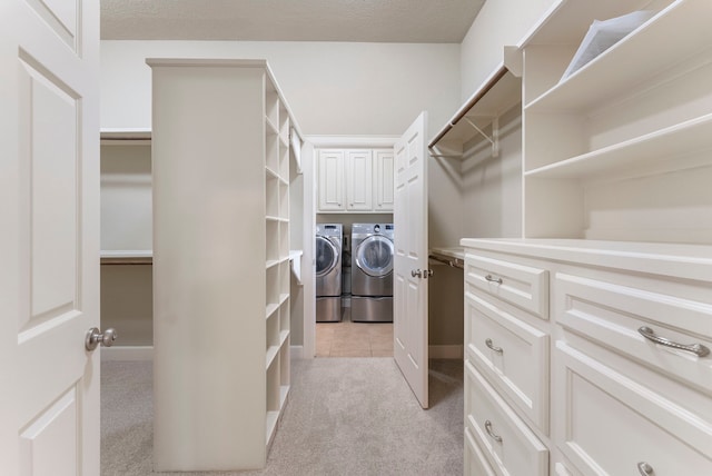 walk in closet with light colored carpet and washer and clothes dryer