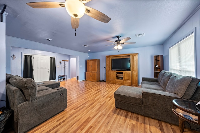 living room featuring ceiling fan, a textured ceiling, and light hardwood / wood-style floors