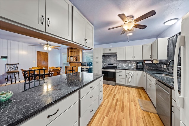 kitchen with stainless steel appliances, a ceiling fan, a sink, light wood-style floors, and backsplash