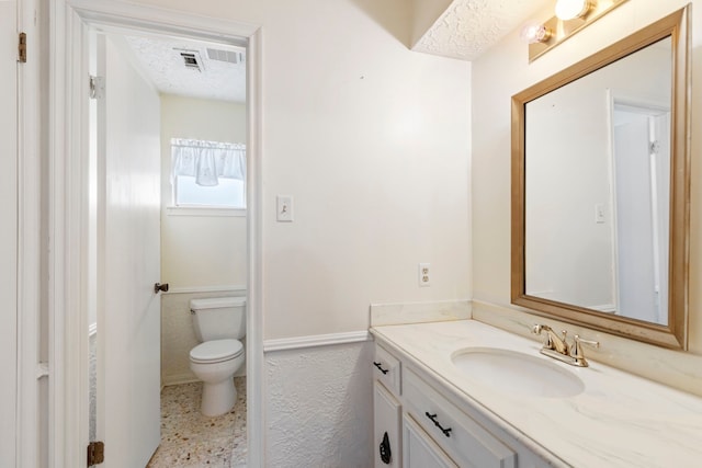 bathroom featuring vanity, toilet, and a textured ceiling