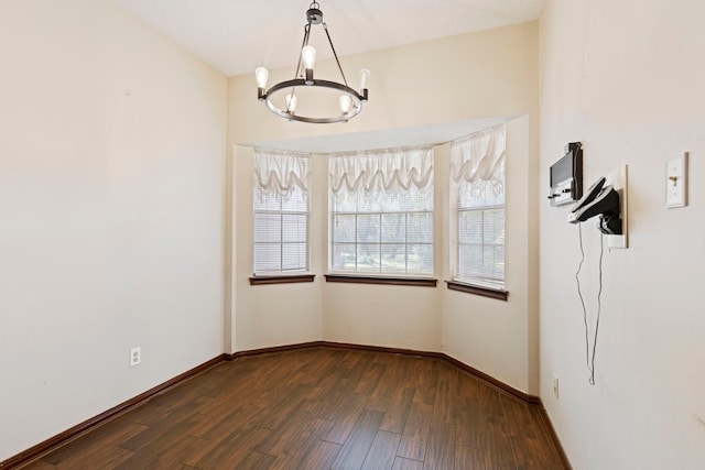 empty room featuring dark wood-type flooring and a chandelier