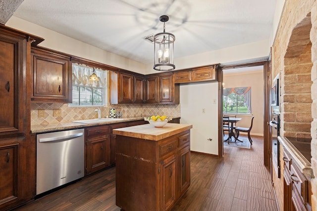 kitchen featuring butcher block counters, a center island, sink, stainless steel dishwasher, and pendant lighting