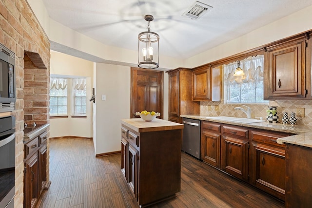 kitchen featuring appliances with stainless steel finishes, tasteful backsplash, sink, a kitchen island, and hanging light fixtures