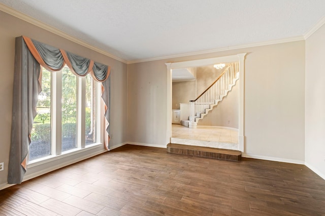 unfurnished room with hardwood / wood-style flooring, ornamental molding, a textured ceiling, and a chandelier