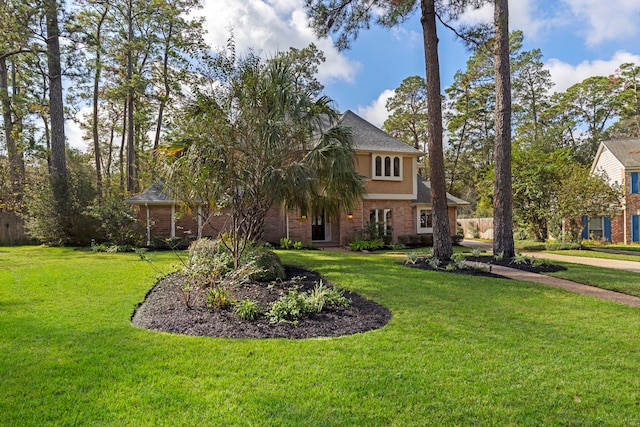 view of front facade with brick siding and a front lawn