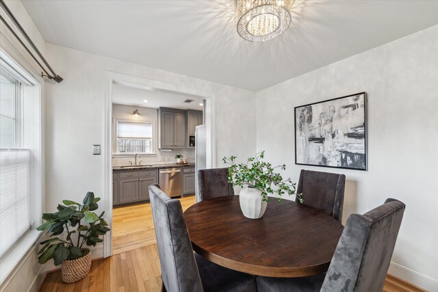 dining area featuring sink, a notable chandelier, and light hardwood / wood-style flooring