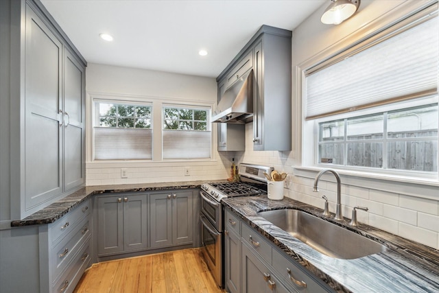 kitchen with gray cabinetry, double oven range, ventilation hood, and dark stone counters