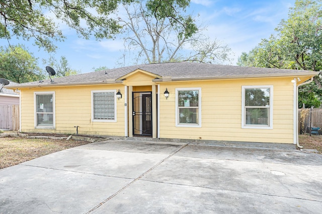 ranch-style house featuring fence, a patio, and roof with shingles