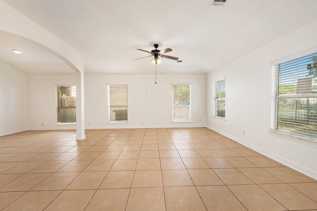 spare room with a ceiling fan, light tile patterned floors, and a healthy amount of sunlight