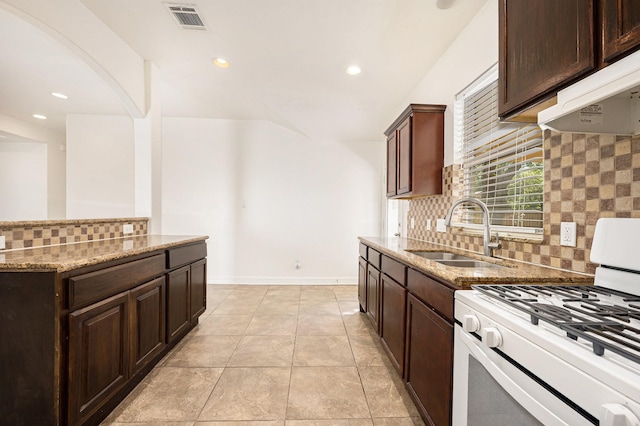 kitchen featuring a sink, under cabinet range hood, white gas range, and light stone countertops