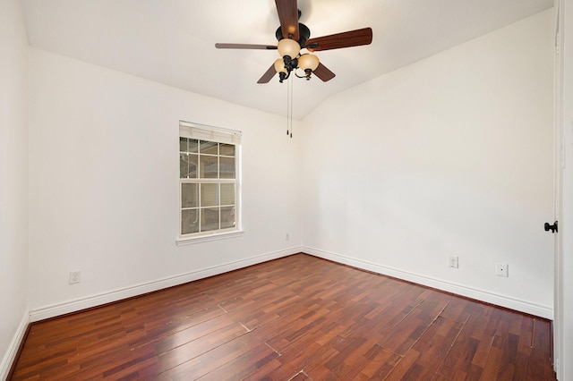 spare room featuring baseboards, ceiling fan, dark wood-style floors, and vaulted ceiling