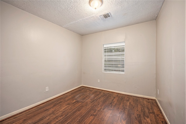 empty room featuring a textured ceiling and dark wood-type flooring