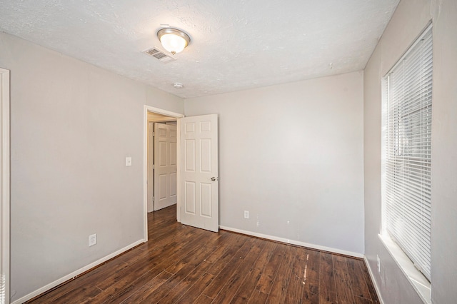 spare room with a textured ceiling and dark wood-type flooring