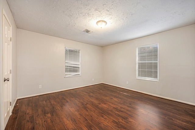 spare room featuring a textured ceiling and dark hardwood / wood-style floors