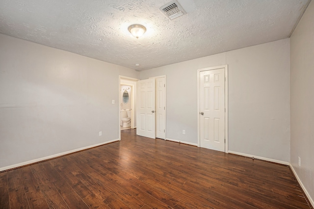 spare room featuring a textured ceiling and dark hardwood / wood-style flooring