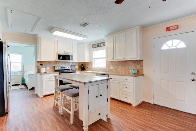 kitchen with a center island, white cabinets, stainless steel appliances, and a wealth of natural light