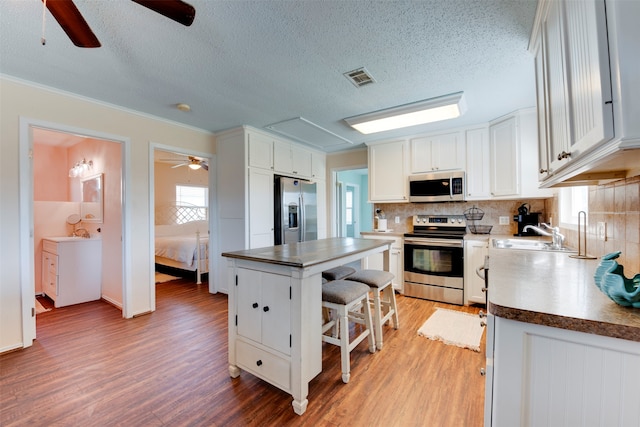 kitchen with a center island, white cabinets, light hardwood / wood-style flooring, and stainless steel appliances