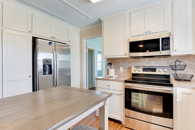 kitchen with backsplash, crown molding, appliances with stainless steel finishes, and white cabinets