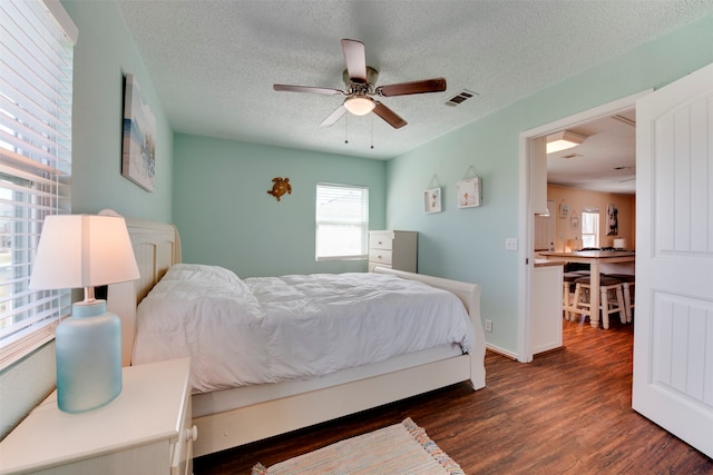 bedroom featuring dark wood-type flooring, a textured ceiling, and ceiling fan