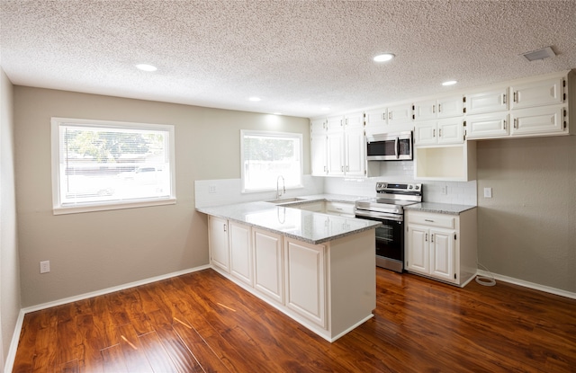 kitchen featuring a wealth of natural light, white cabinets, kitchen peninsula, and stainless steel appliances