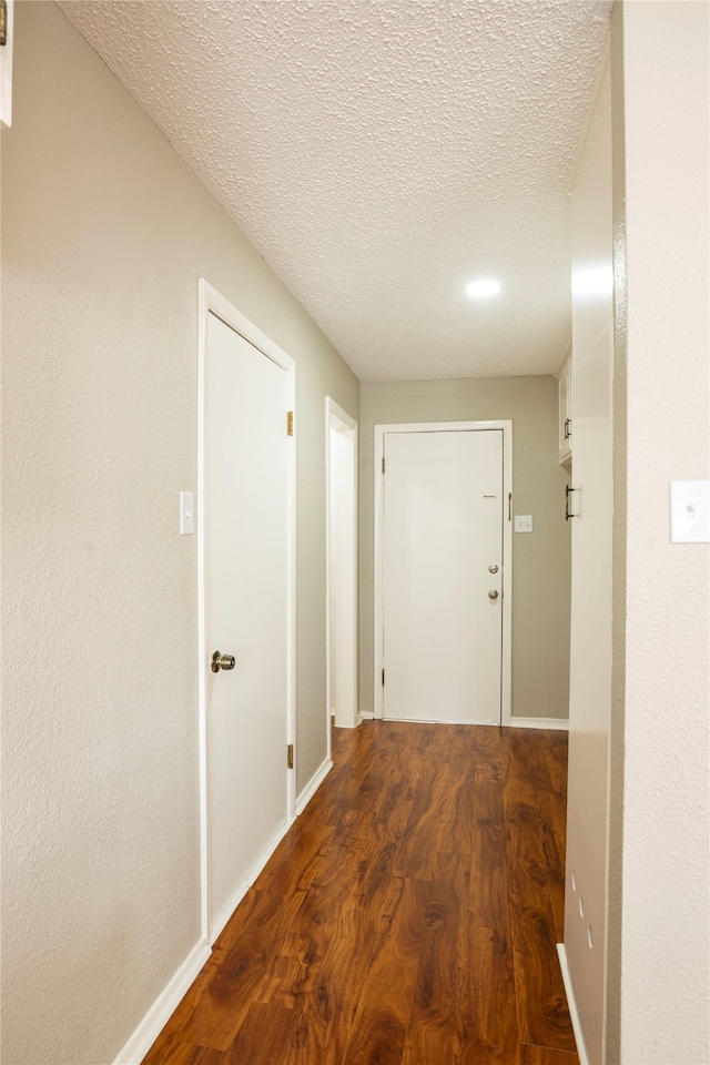 hallway with wood-type flooring and a textured ceiling