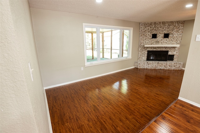 unfurnished living room with dark hardwood / wood-style floors, a textured ceiling, and a fireplace