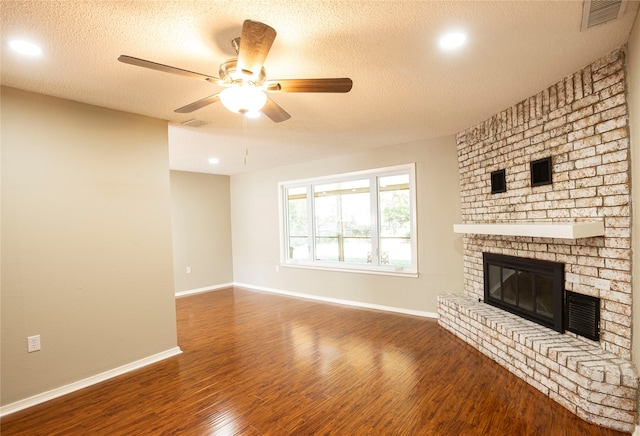 unfurnished living room featuring ceiling fan, a textured ceiling, dark hardwood / wood-style flooring, and a fireplace