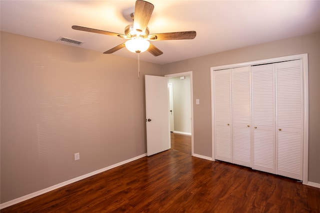 unfurnished bedroom with dark hardwood / wood-style flooring, a closet, and ceiling fan