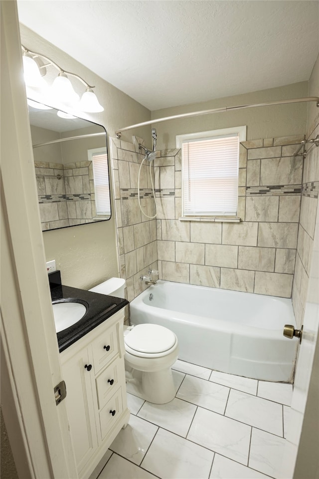 full bathroom featuring a textured ceiling, toilet, vanity, tiled shower / bath combo, and tile patterned flooring