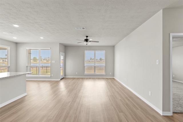 unfurnished living room featuring light hardwood / wood-style floors, ceiling fan, and a textured ceiling