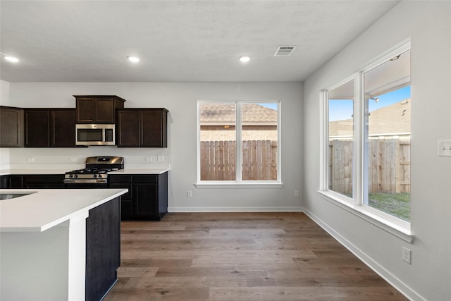 kitchen with light countertops, appliances with stainless steel finishes, wood finished floors, and baseboards