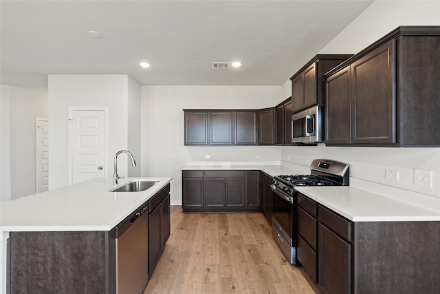 kitchen with light wood-type flooring, dark brown cabinets, stainless steel appliances, and a sink