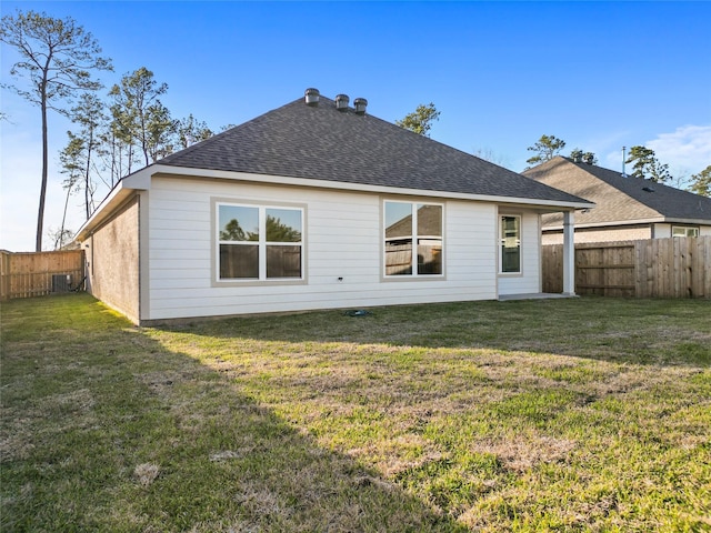 back of house featuring a fenced backyard, a lawn, central AC unit, and roof with shingles