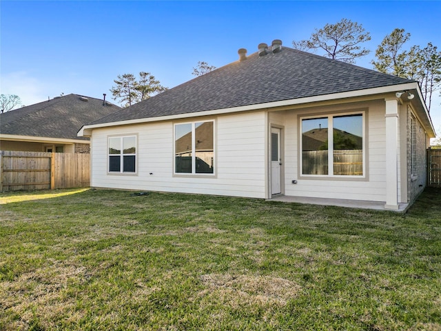 back of house with a fenced backyard, roof with shingles, and a yard